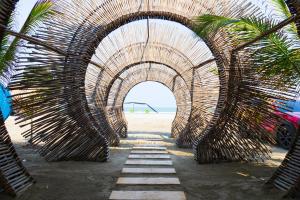 a wooden tunnel on a beach with a palm tree at Coco Beach Hotel - Rooftop & Beach Club in Cartagena de Indias
