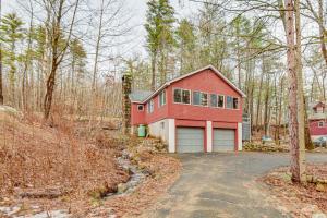 a red house with a garage in the woods at Inviting Alton Bay Home Near Lake Winnipesaukee! in Alton Bay