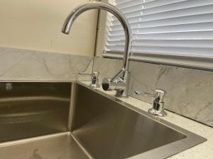 a stainless steel kitchen sink with a faucet at House in Thomastown in Melbourne