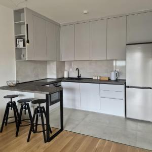 a kitchen with white cabinets and a table and stools at Apartman Nocturno Trebinje in Trebinje