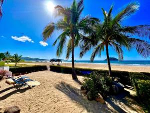 una playa con 2 palmeras y una playa de arena en Beachfront Villa, en Rincón de Guayabitos