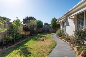 a backyard of a house with a fence at Charming Cottage, 7 mins walk to the beach and golf! in Torquay