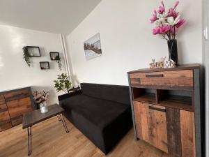un soggiorno con divano nero e fiori sul muro di Apartman “Timravy” a Martin