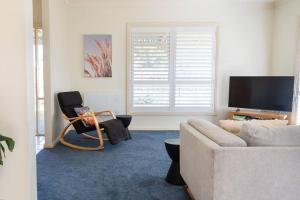 a living room with a couch and a tv at Charming Cottage, 7 mins walk to the beach and golf! in Torquay
