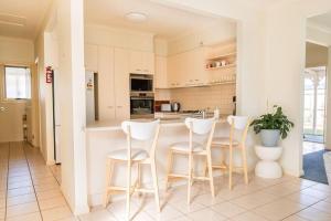 a kitchen with white stools and a counter top at Charming Cottage, 7 mins walk to the beach and golf! in Torquay