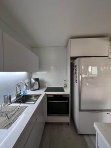 a white kitchen with a refrigerator and a sink at Saloniky Garden in H̱olon +12 photos