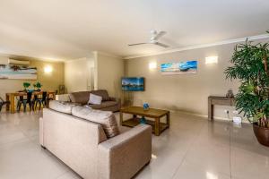 Postcard Perfect - Cairns Nine Pool Tropical Oasis في Westcourt: غرفة معيشة مع أريكة وطاولة