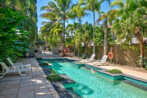 Postcard Perfect - Cairns Nine Pool Tropical Oasis في Westcourt: مسبح مع كراسي الصالة والنخيل