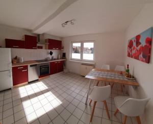 cocina con armarios rojos, mesa y sillas en Charmante Maisonnette-Dachgeschosswohnung in zentraler Lage, en Rostock