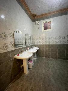 a bathroom with two sinks and two mirrors at شالية الفوز in Medina