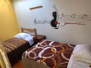 a room with two beds and a painting on the wall at Hospedaje Luciano in Ayacucho