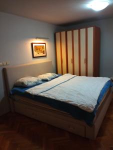 Bett mit einem Kopfteil aus Holz in einem Schlafzimmer in der Unterkunft Hostel Lejla in Podgorica
