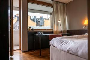 a hotel room with a bed and a desk and a window at Scandic Anglais in Stockholm