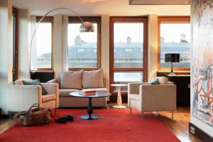 uma sala de estar com um sofá, cadeiras e janelas em Scandic Anglais em Estocolmo