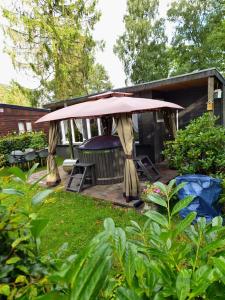 een tuinhuisje met een tafel en stoelen in de tuin bij Chalet met hottub in Lanaken