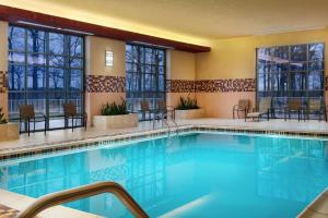 a pool in a hotel room with chairs and tables at Embassy Suites by Hilton Charlotte Concord Golf Resort & Spa in Concord