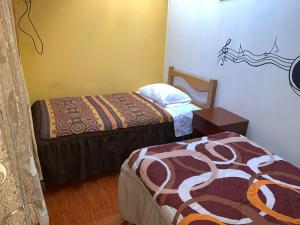 - une chambre avec deux lits, une table et un couvre-lit dans l'établissement Hospedaje Luciano, à Ayacucho