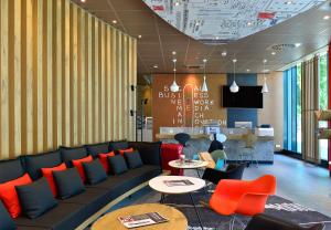 eine Lobby mit einem Sofa, einem Tisch und Stühlen in der Unterkunft Ibis Muenchen City Ost in München