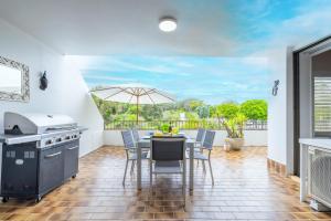 cocina con mesa con sillas y sombrilla en 14 The Dunes large unit with pool tennis court and directly across from Fingal beach, en Fingal Bay