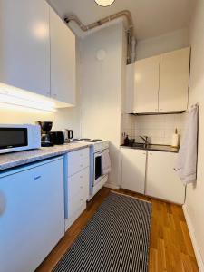 una cucina con armadi bianchi e un tappeto bianco e nero di Your Chic Vibrant Airbnb a Helsinki Altre 16 foto