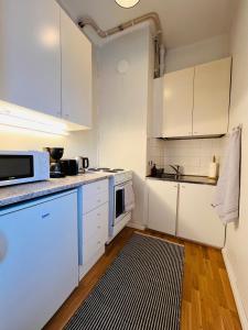 uma cozinha com armários brancos e um tapete preto e branco em Your Chic Vibrant Airbnb em Helsínquia