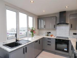 a kitchen with gray cabinets and a sink and windows at Apt 9 Hunter's Quay in Bridlington