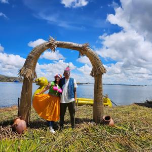 a man and woman standing under an arch on a lake at Sol del TITICACA lodge in Uros