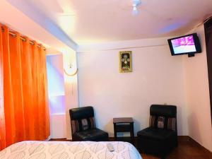a bedroom with two chairs and a bed and a tv at Tierra Mágica Hostal in Machu Picchu