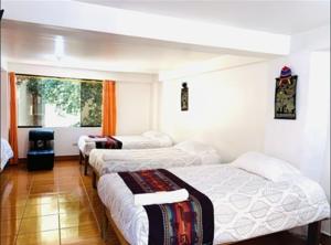 Cette chambre comprend 3 lits et une fenêtre. dans l'établissement Tierra Mágica Hostal, à Machu Picchu