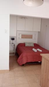1 dormitorio con 1 cama roja y 2 toallas en Monoambiente Atenea B en Chivilcoy