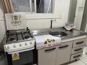 a small kitchen with a stove and a sink at Apartamento no Centro de Blumenau in Blumenau