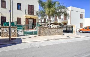 a building with a palm tree in front of a street at Casa Antonella in San Vito lo Capo