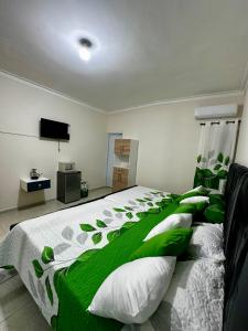 a bedroom with a bed with a green and white comforter at Hotel Mi Dulce Amanecer PyR in Nagua