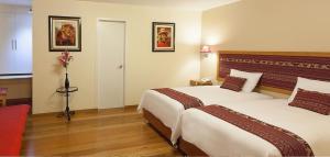 een hotelkamer met 2 bedden en een rode bank bij Tandapata Boutique Hotel in Cuzco