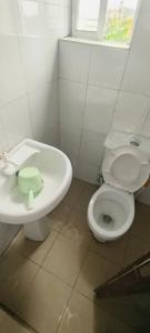 a white bathroom with a toilet and a sink at Rocket Room Hotel & Suites Limited in Port Harcourt