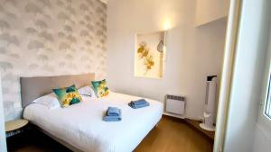 1 dormitorio con 1 cama blanca y 2 toallas en KOSY Spa, Les Princes, en Cannes
