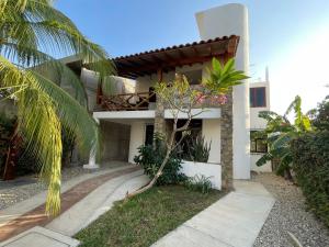 a white house with a palm tree in front of it at Departamento Ninfa "Alojamiento Completo" in Puerto Escondido