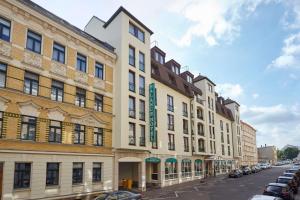 eine Reihe von Gebäuden auf einer Straße mit parkenden Autos in der Unterkunft Balance Hotel Leipzig Alte Messe in Leipzig