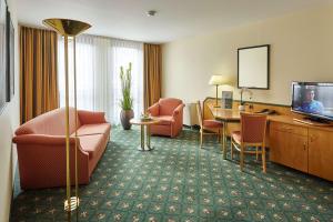 ライプツィヒにあるバランス ホテル ライプチヒ アルテ メッセのテーブルと椅子、テレビが備わるホテルルームです。