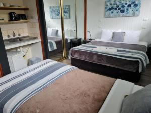 a hotel room with two beds and a bathroom at Tall Timbers Motel in Dungog