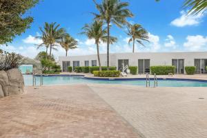 a swimming pool with palm trees and a building at 15th Floor Luxury Suite at Trump Int Resort in Sunny Isles Beach