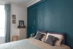 een slaapkamer met blauwe muren en een bed met kussens bij Cozy 30 m love nest in Levallois-Perret in Levallois-Perret