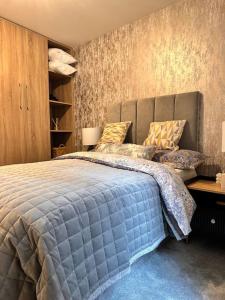 a bedroom with a large blue bed with pillows at Luxurious Flat at Leicester Town in Leicester