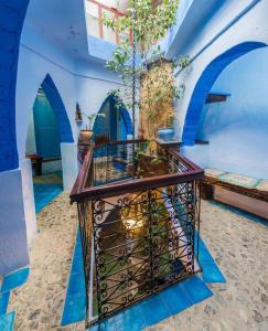 Hotel Molino Garden في شفشاون: غرفة زرقاء وبيضاء مع طاولة فيها زرع