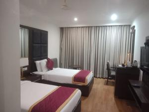 a hotel room with two beds and a desk at Hotel Comfortel Banjara Hills- Free Buffet breakfast- Multi Cuisine Restauran- An Svm Brand in Hyderabad