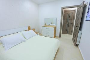 ein weißes Schlafzimmer mit einem weißen Bett und einer Kommode in der Unterkunft 3 bed Akid Lotfi with parking in Bir el Djir