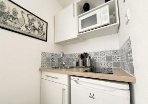 uma pequena cozinha com um micro-ondas e um lavatório em Alger Lodge em Nantes