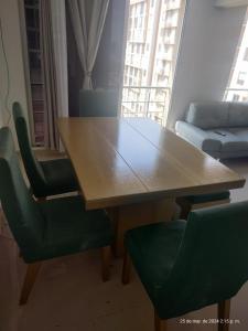 una mesa de madera y 2 sillas verdes en la sala de estar. en Bello Apto Zona Norte, Cerca al Malecon en Barranquilla