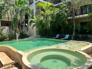 Casa Tulum Hotel في تولوم: مسبح مع حوض استحمام ساخن في مبنى