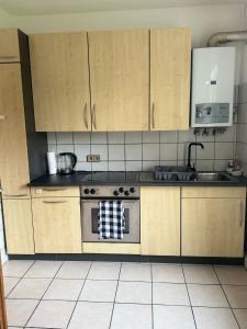 uma cozinha com armários de madeira e um forno com placa de fogão em HomeStay em Bochum